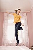 A teenage girl jumping on her bed