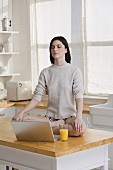 A woman meditating with a laptop