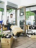 A man pushing a trolley of wine crates into a wine shop