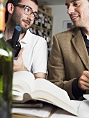 Two friends with books and bottles of wine at a wine tasting session