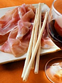 Parma ham with grissini; red wine glass
