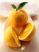 Orange und Orangenhälften auf Teller