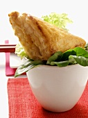 Filled puff pastry parcels on mixed salad