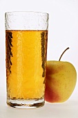 Glass of apple juice beside fresh apple