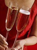 Woman in red dress holding two different champagne glasses