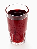 Red grape juice in glass with drops of water
