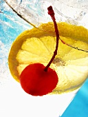 Drink with slice of lemon and cocktail cherry (detail)