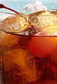 Drink with rum, ice cubes and cocktail cherry (detail)