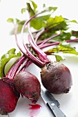 Beetroot with leaves, whole and halved; knife