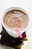 Cocoa in paper cup with straw on pieces of chocolate