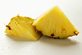 Two wedges of pineapple with drops of water