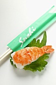 Nigiri sushi with shrimp on shiso leaf; chopsticks