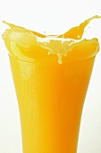Orange juice splashing out of glass