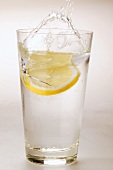 Lemon falling into glass of water