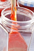 Kitchen spoon with strawberry jam in jam jar