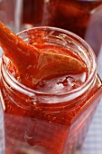 Strawberry jam in jar with kitchen spoon
