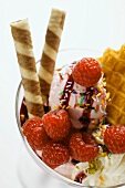 Sundae with raspberry ice cream, cream, wafers & sprinkles