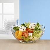 Salad ingredients in glass bowl in front of window