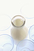 Milk bottle among empty glasses (overhead view)