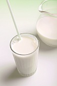 Glass of milk with straw beside milk jug