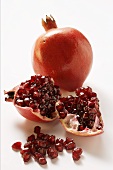 Two pomegranates, one halved; pomegranate seeds