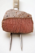 Beef steak, a piece cut off, on meat fork