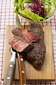 Beef steaks, partly sliced, salad