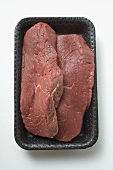 Two slices of beef sirloin in polystyrene tray