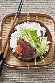 Raw tuna fillet with poppy seeds, rice and salad