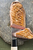 Roast duck breast, a piece cut off, on knife