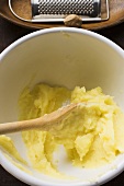 Remains of mashed potato in bowl, nutmeg with grater