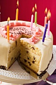 Birthday cake with burning candles, a piece cut