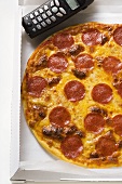 Pizza mit Salami und Käse im Pizzakarton mit Telefon