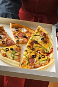 Verschiedene Pizzastücke im Pizzakarton