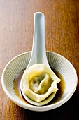 Pasta parcel on spoon in soy sauce