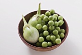 Green baby aubergines in wooden bowl