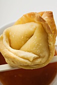 One deep-fried wonton with sweet and sour sauce (close-up)