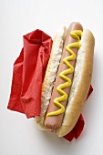 Hot dog with mustard on red paper napkin