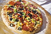 Pepperoni pizza with peppers and olives on wooden plate