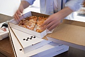 Man dividing up Pizza Margherita in pizza box