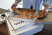 Man dividing up Pizza Margherita in pizza box