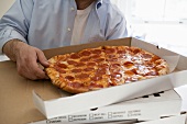 Man holding pizza box containing pepperoni pizza