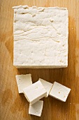 Block of tofu and diced tofu on wooden background