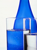 Two glasses of water in front of blue water bottle
