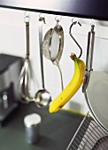 Banane und Küchenwerkzeuge hängen an Haken in der Küche