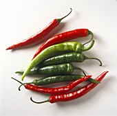 Four red and four green chili peppers on white background