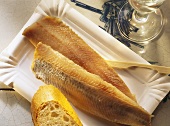 Two matje herrings with bread in cardboard dish