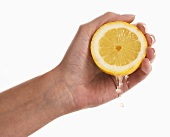 Frauenhand zerdrückt eine Zitrone