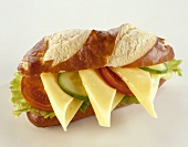Pretzel roll topped with cheese, tomatoes, cucumber, lettuce