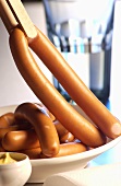 Hot dog sausages held in tongs